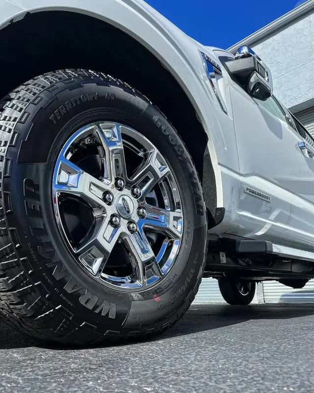 Clean chrome wheel and dressed tyre on a white Ford F-150